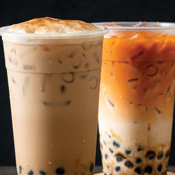 Two iced bubble teas, one light brown with foam and cinnamon, the other orange with tapioca pearls.