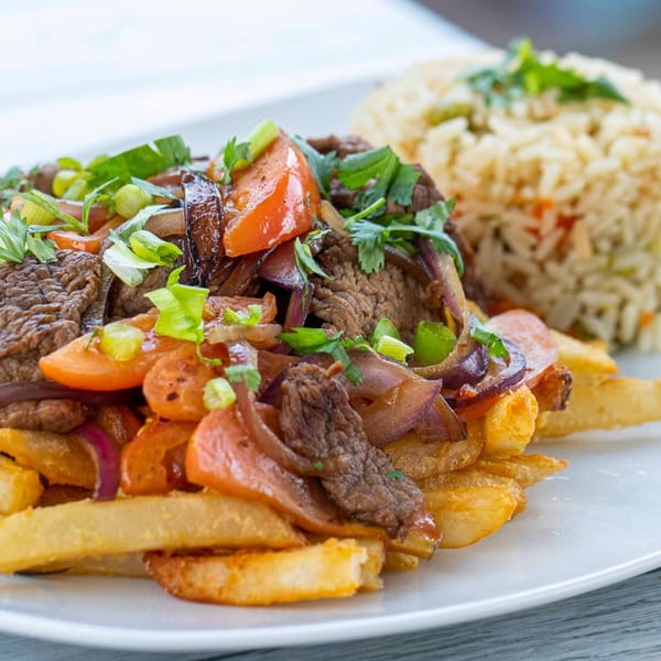 El Pollo Asado's Lomo Saltado features steak, tomatoes, onions, and fries, served with rice.
