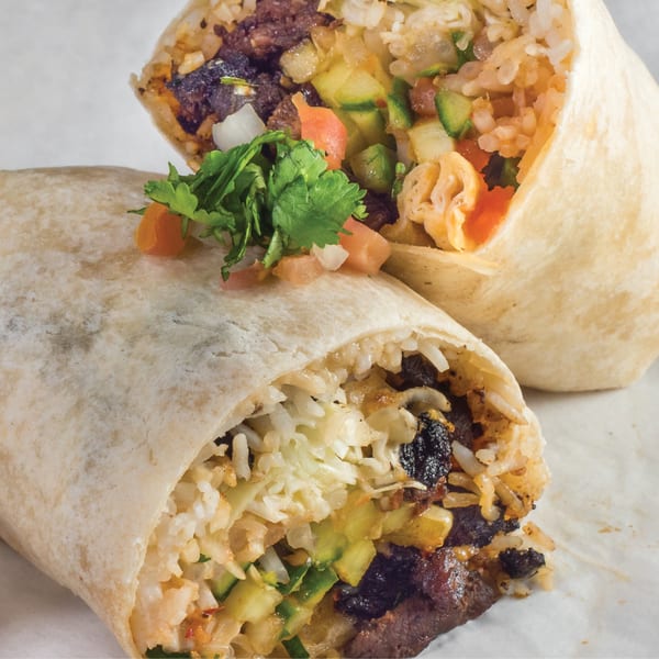 Two El Pollo Asado burritos, one cut open to reveal rice, beans, and fresh vegetables.
